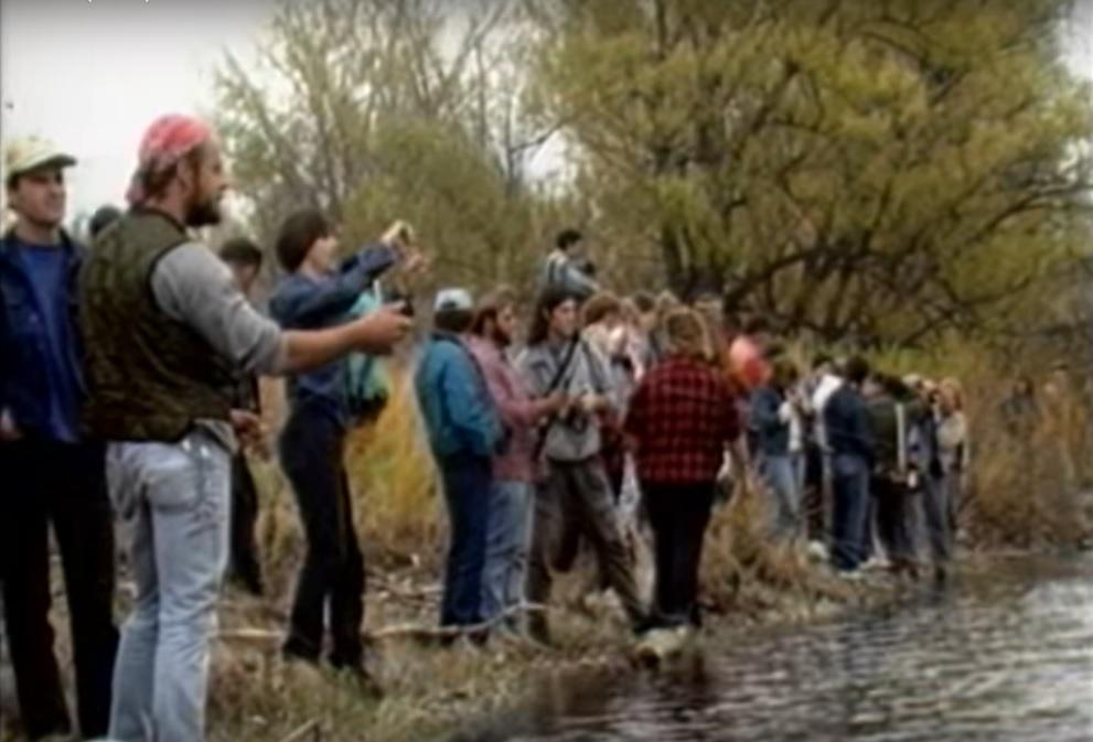 A group of people fishing on the bank of a river.
